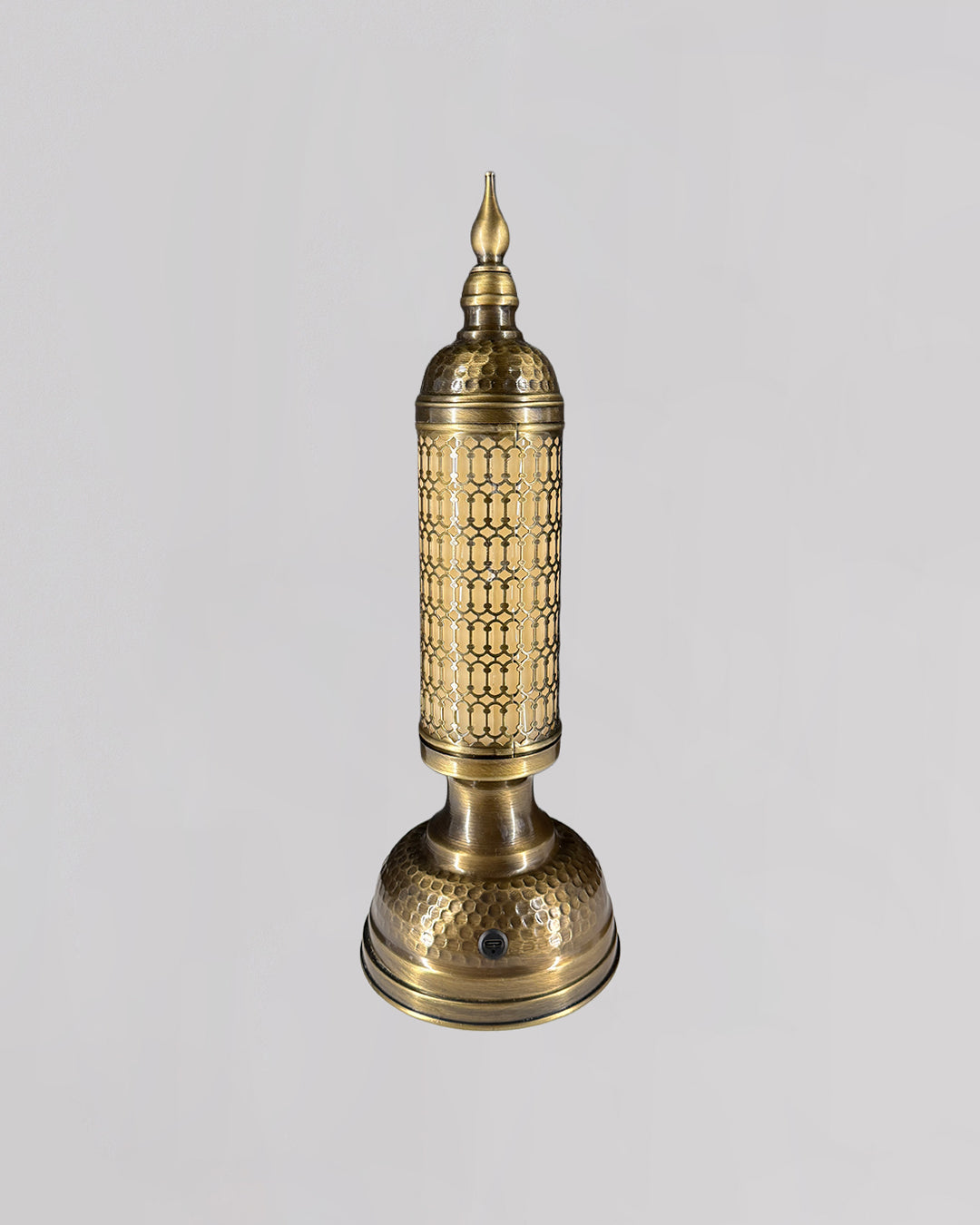 Decorative brass lamp with intricate patterns on a light gray background