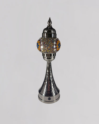 Decorative silver lamp with a colorful glass shade on a gray background