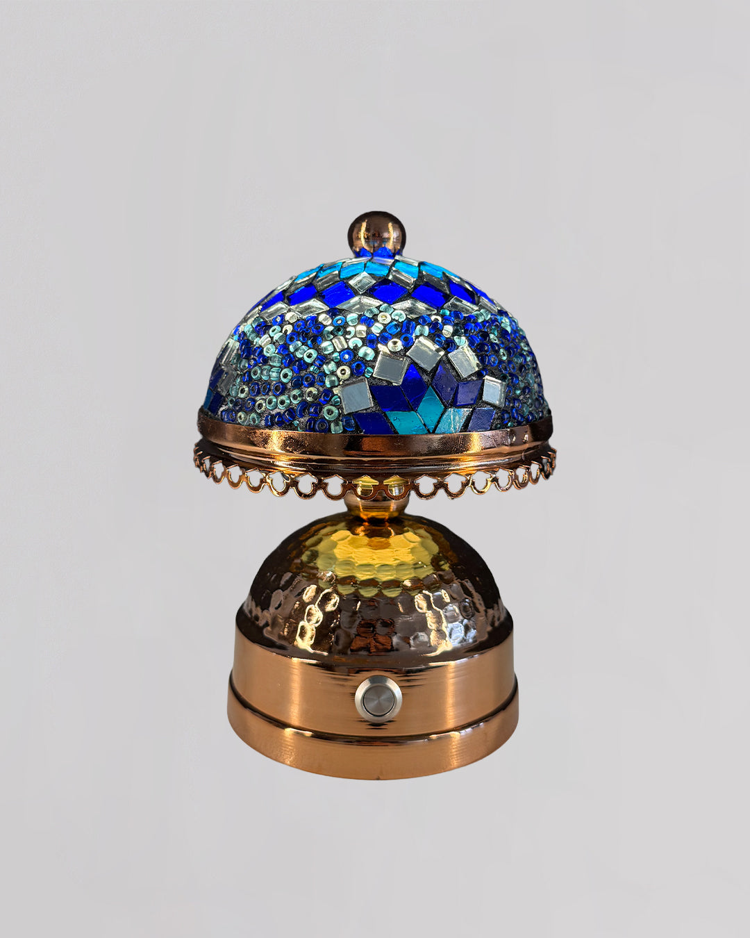 Decorative object with blue mosaic top and gold base on a light gray background